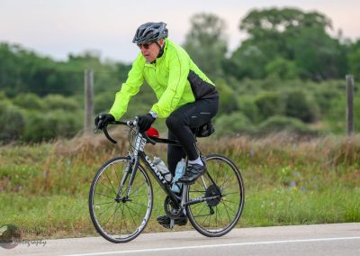 Bright green cycling jacket, road bike, and outdoor scenery for Bluebonnet Express imagery.