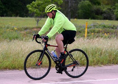Velo cyclist on a scenic outdoor trail wearing high-visibility gear for safety and comfort.