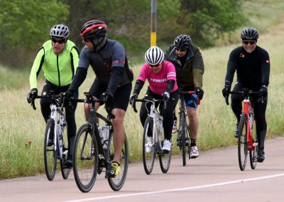 Vibrant group of cyclists enjoying a ride on a scenic trail with lush greenery, promoting outdoor cycling and fitness.