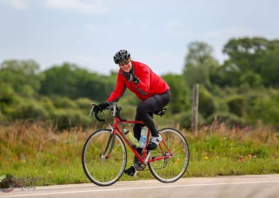 Vibrant cyclist in red jacket enjoying a ride on scenic outdoors near bluebonnets and greenery.