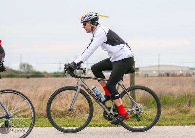 Bright cyclist riding a mountain bike on a scenic trail with the Bluebonnet Express logo.