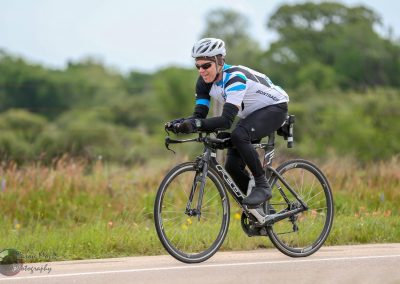 Highway cyclist riding a road bike on open countryside during daytime.