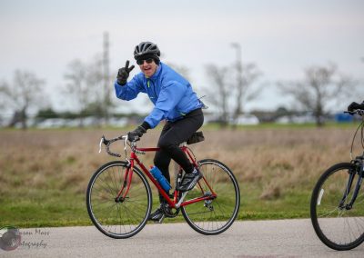 Bright blue jacket cyclist riding a red bike outdoors during daytime.