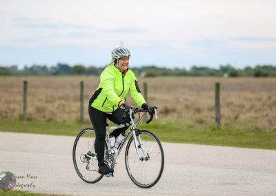 Bright yellow jacketed cyclist enjoying a ride on a scenic rural bike path during daytime.