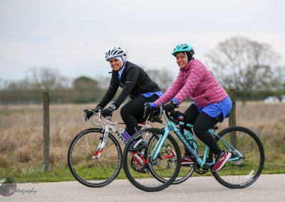 Women biking on a scenic trail with bikes and helmets, enjoying outdoor cycling adventure.