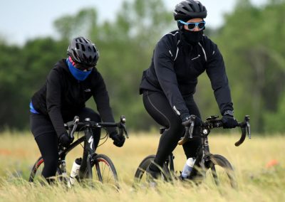 Bike riding in outdoor nature setting during daytime, wearing helmets and cycling gear for safety.