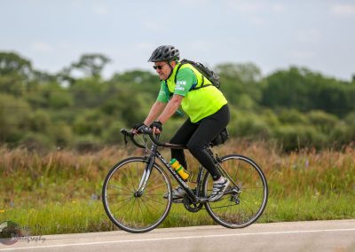 Experienced cyclist riding a blue bike on scenic outdoor trail during daytime.
