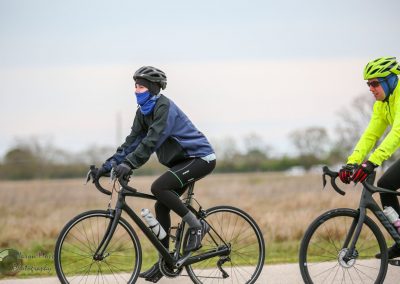 Cyclists riding on a scenic trail during daytime with cloudy weather.
