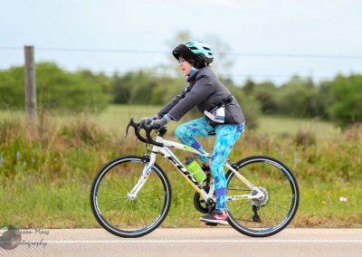 Bright woman cycling outdoors with Bluebonnet Express bike, promoting eco-friendly transportation and bike tours.
