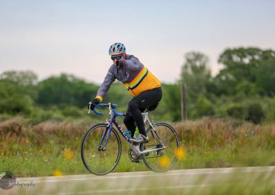 Vibrant cyclist riding through scenic countryside on Bluebonnet Express route.