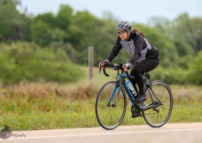 Bright blue road bike riding through lush green landscape in Texas, part of Bluebonnet Express cycling tour.