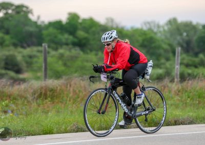 Vibrant cyclist riding a Cannondale road bike outdoors in nature for Bluebonnet Express event.