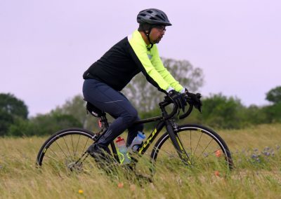 High-performance cyclist riding on a trail wearing a helmet and neon jacket.