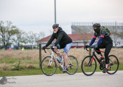 Adventure cyclists riding bikes outdoors on a paved trail in a scenic park.