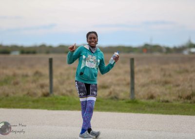 Happy woman running outdoors holding water bottle on a cloudy day.