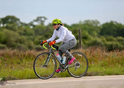 Bright woman riding a Specialized road bike on a rural trail, enjoying outdoor cycling adventure.