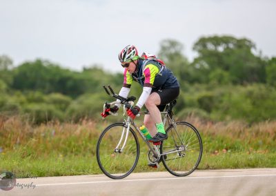 Vibrant cyclist racing on a scenic outdoor route with scenic greenery background.