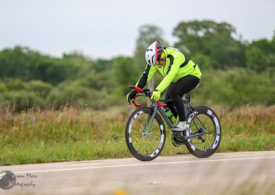 High-performance electric bike riding through rural landscape under cloudy sky.