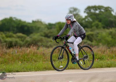 Bright woman cycling on a scenic outdoor trail, promoting fitness and outdoor adventure.