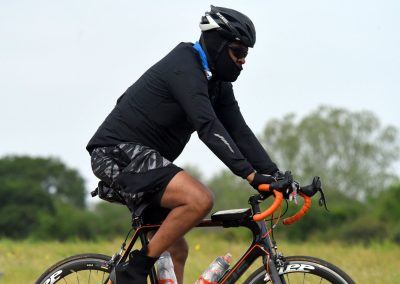 High-performance cycling with a rider wearing a helmet, sunglasses, and black gear on a sleek road bike.
