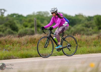 Vibrant female cyclist riding a bike outdoors on scenic trail, emphasizing active outdoor lifestyle and fitness.