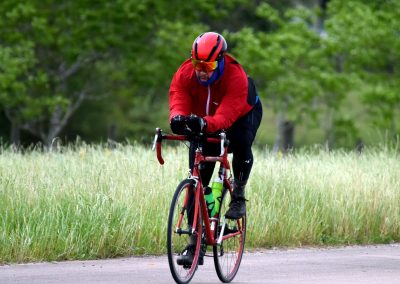 Vibrant cyclist riding on scenic trail with lush green trees, emphasizing outdoor biking adventure.