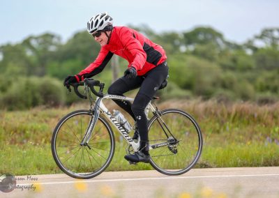Vibrant cyclist riding a Specialized road bike on a scenic outdoor trail in Texas.