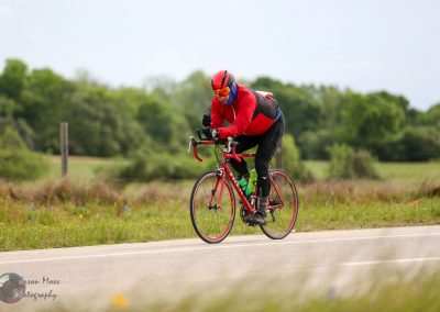Vast cycling landscape with rider in red jacket on Bluebonnet Express bike trail at Texas countryside.