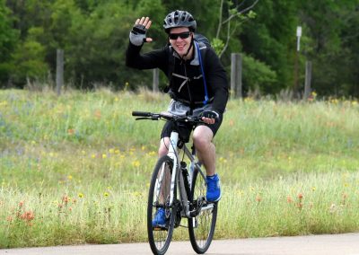 Bright cyclist riding on a trail surrounded by wildflowers and lush greenery, promoting outdoor biking adventures.