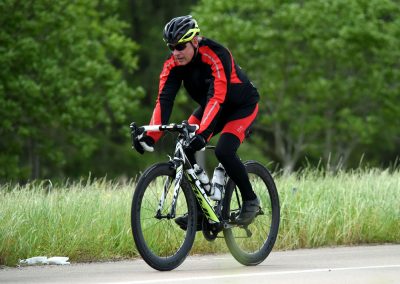 Vibrant cyclist riding on a scenic rural road during daytime for Bluebonnet Express event.