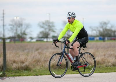 Bright yellow cycling jacket and helmet worn by cyclist riding a bike outdoors on a cloudy day.
