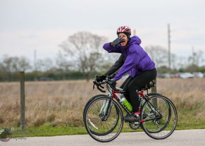 Vibrant woman riding a bike in outdoors, wearing purple jacket and helmet, enjoying cycling adventure.