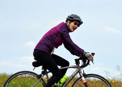 Vibrant female cyclist riding mountain bike in floral field, enjoying outdoor adventure.