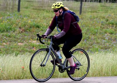 Bright yellow helmet on cyclist enjoying a scenic bike ride along a trail with wildflowers in the background.