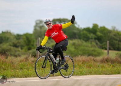 Cyclist riding a bike in a scenic outdoor setting, promoting Bluebonnet Express cycling tour.