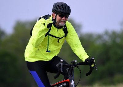 High-energy cyclist in bright yellow jacket smiles on mountain bike ride outdoors.