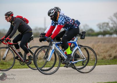 Vibrant cyclists riding through open countryside on Bluebonnet Express bike route.