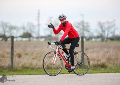 Bright red biking jacket, smiling woman riding a sports bike outdoors in fall.