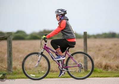 Bright pink mountain bike on a countryside trail during daytime with a woman rider.