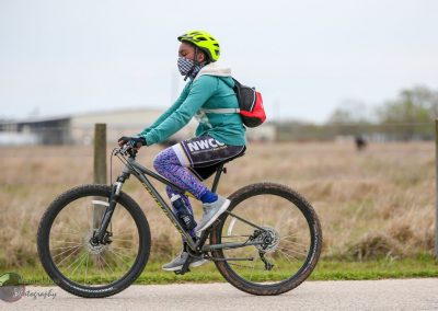 Bright green helmet, face mask, and athletic gear on cyclist riding a mountain bike outdoors.
