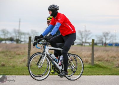 Riders in blue and red jerseys cycling outdoors on a cloudy day, promoting Bluebonnet Express bike tours.