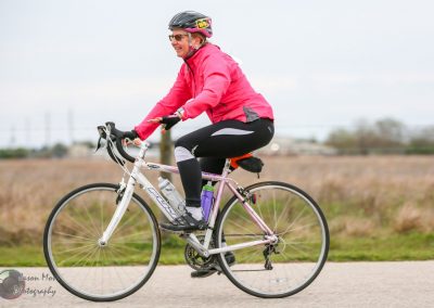 Bright pink cyclist jacket and helmet on a white bicycle enjoying a ride outdoors.