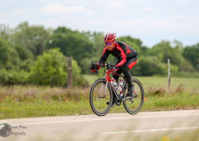 High-performance cyclist riding a road bike in scenic countryside for Bluebonnet Express event.