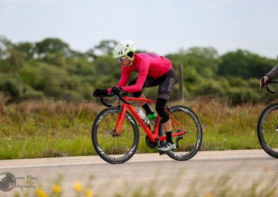 Vibrant cyclist riding a road bike on open highway during daytime for Bluebonnet Express event.