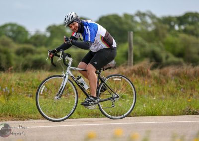 Vibrant cyclist on a bike during a scenic ride with a lush green background and clear skies.