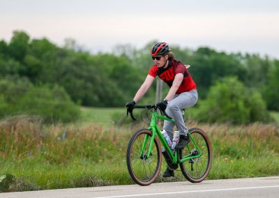 Vegan cyclist riding a bright green e-bike on a scenic rural trail.