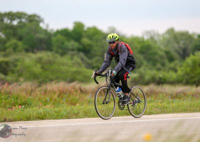 Bright yellow helmet, biking on scenic trail with green landscape, promoting outdoor cycling adventures.