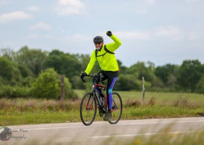 Bright yellow cycling jacket on man riding bike outdoors on country road.