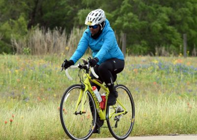Vibrant bluejacket rider on yellow bicycle in colorful wildflower field during daytime.