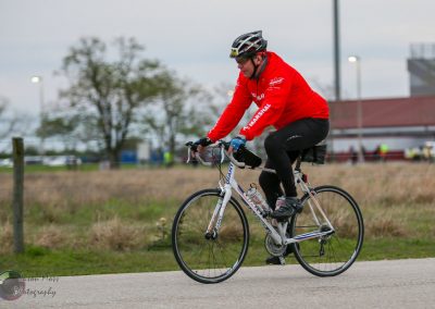 Man cycling outdoors on a road bike in a park or recreational area.